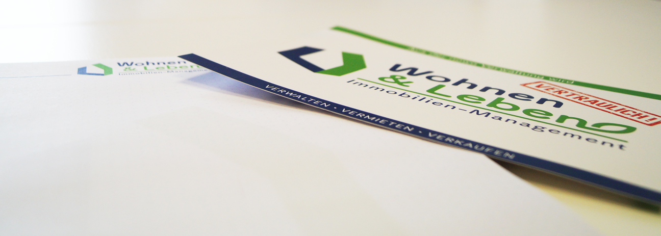 Zwei Flyer der Immobilienverwaltung Wohnen und Leben liegen auf einem Tisch