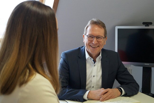 Geschäftsführer Andreas Lang sitzt einer Frau gegenüber und führt eine Beratung